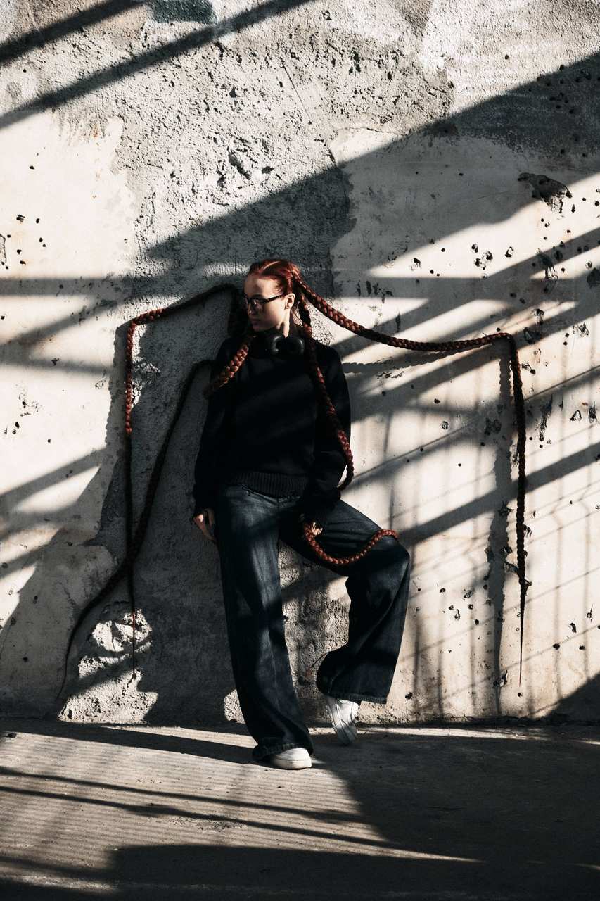 Editorial: very long red braids across a concrete wall
