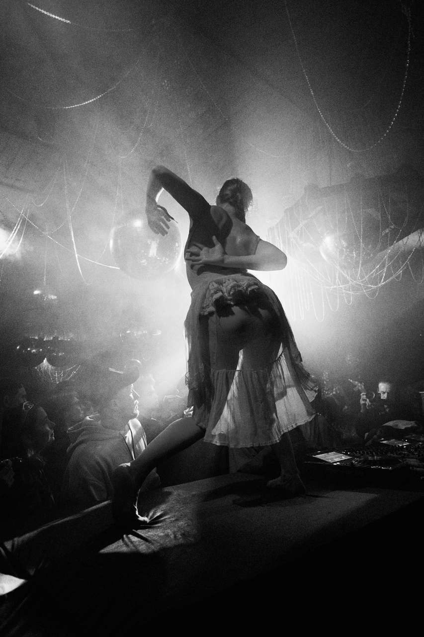 A backlit figure raising both arms in a smoky dark room