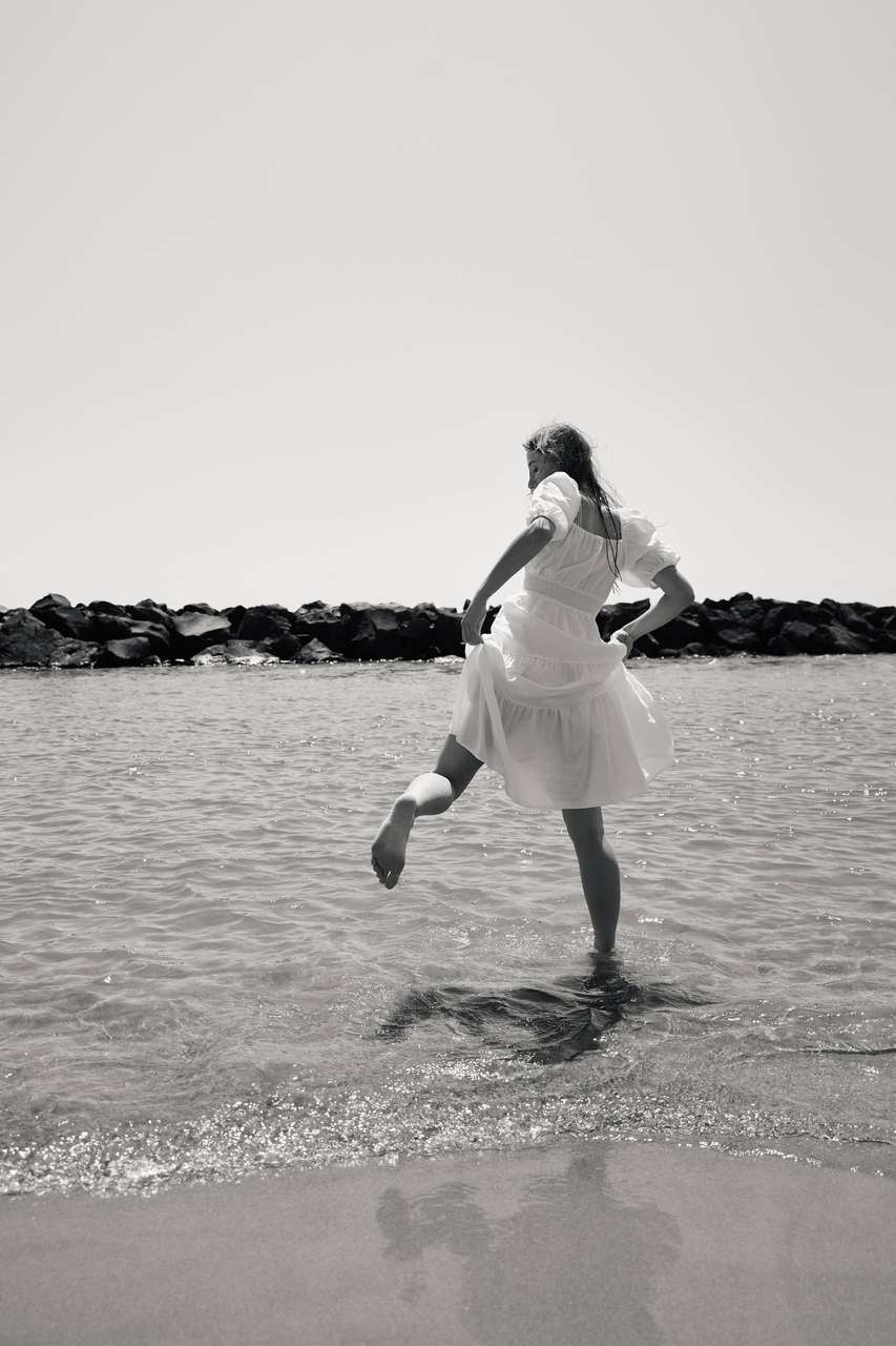 A figure in white clothing crossing a pale desert flat