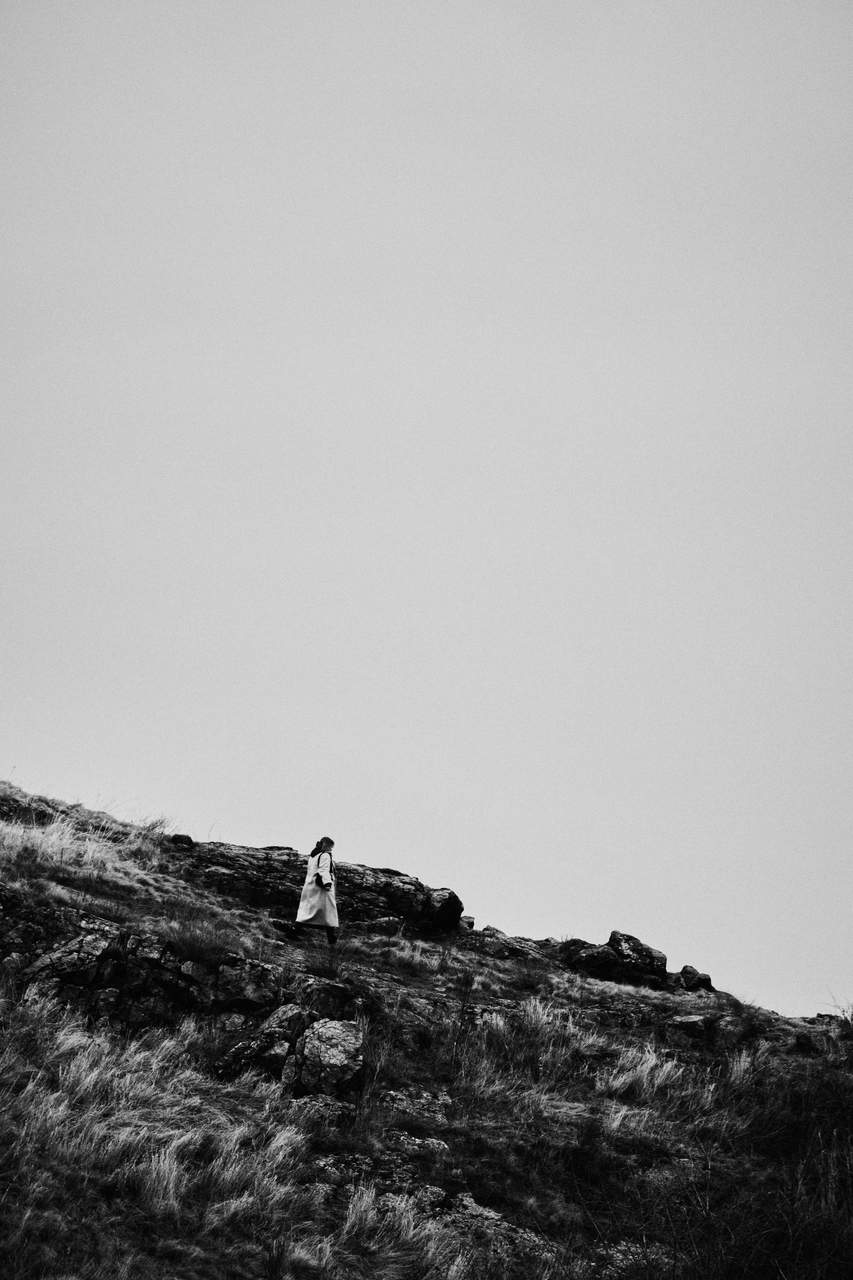 Black and white person on a rocky hill under an overcast sky