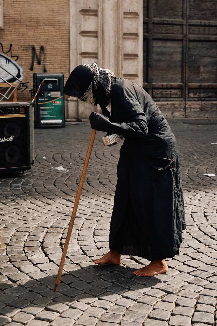 A person in dark clothing bending over on a city street