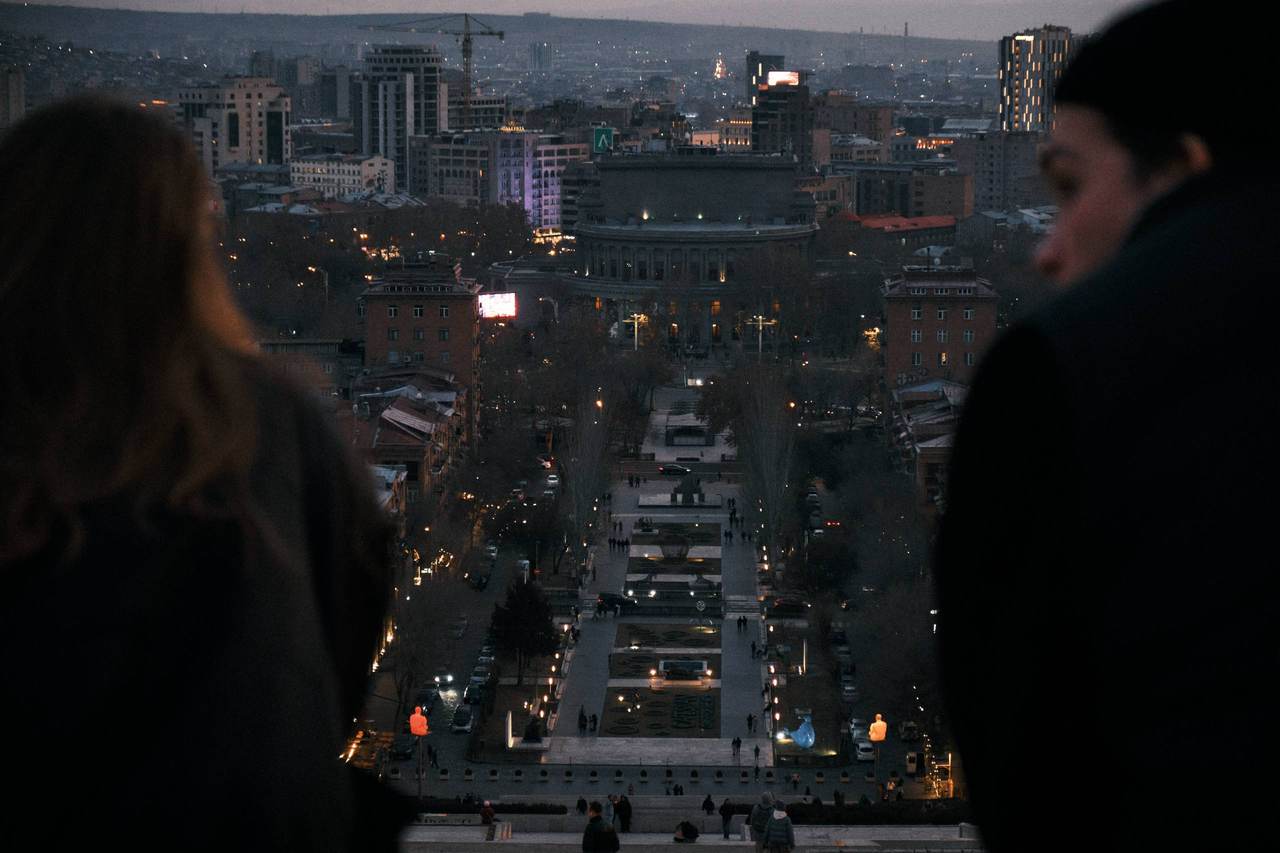 Two people seen from behind facing city lights at night