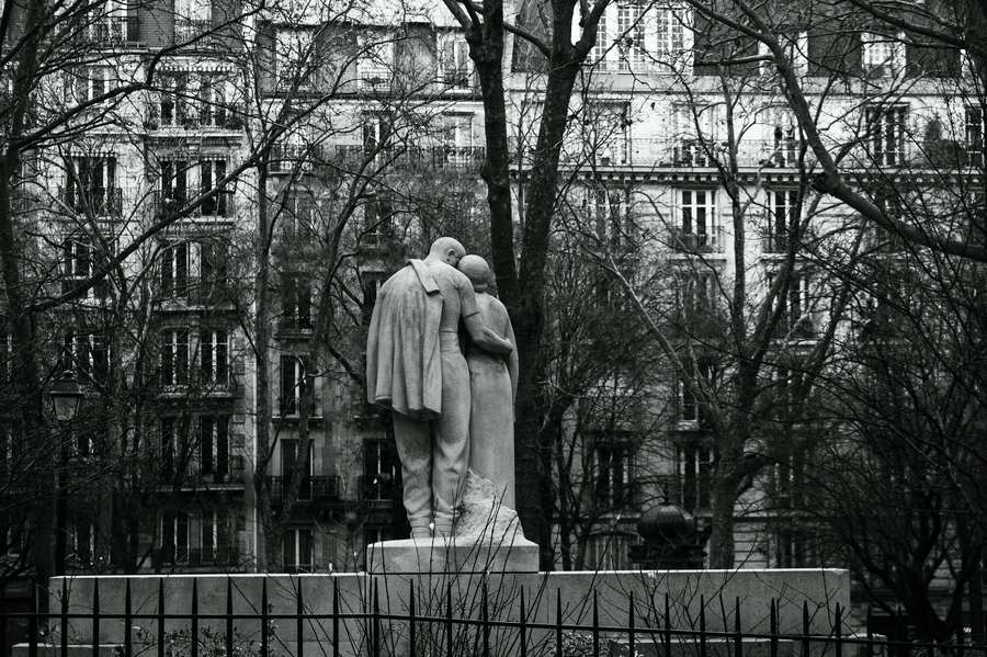 A stone statue on a tree-lined embankment