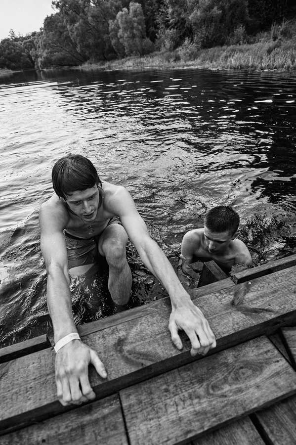Black and white two people crouching in a shallow stream