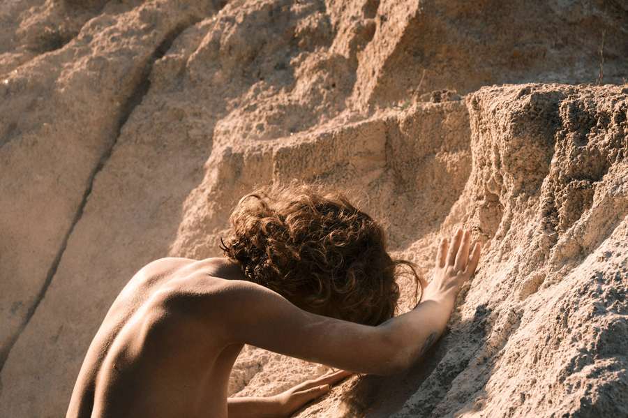 A hand touching the surface of a sandstone cliff