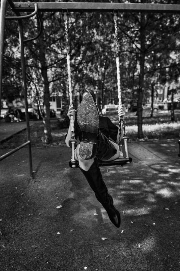 Black and white figure crouching among trees